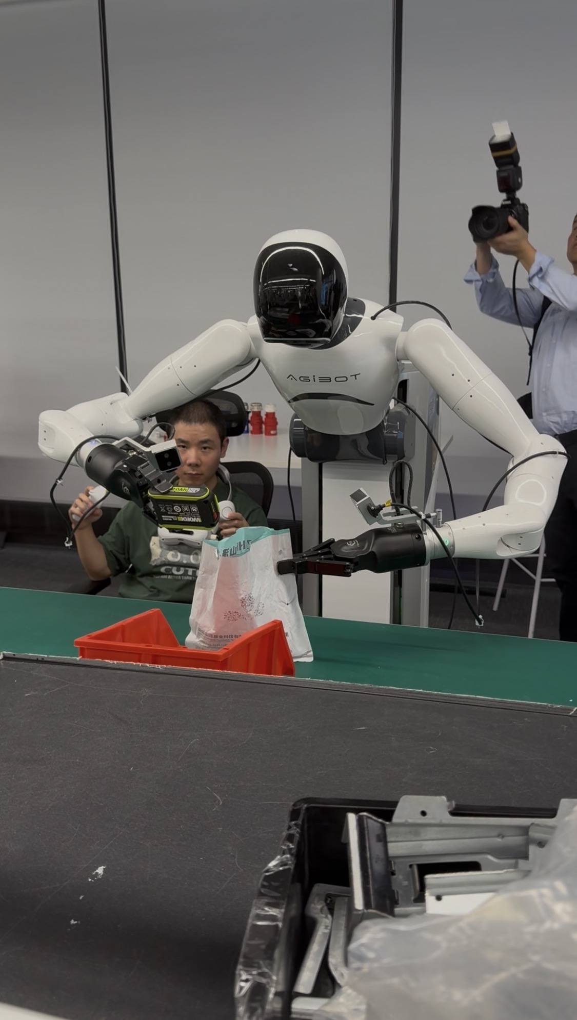 Robot humanoïde portant la marque AGIBOT devant un convoyeur lors d'une démonstration