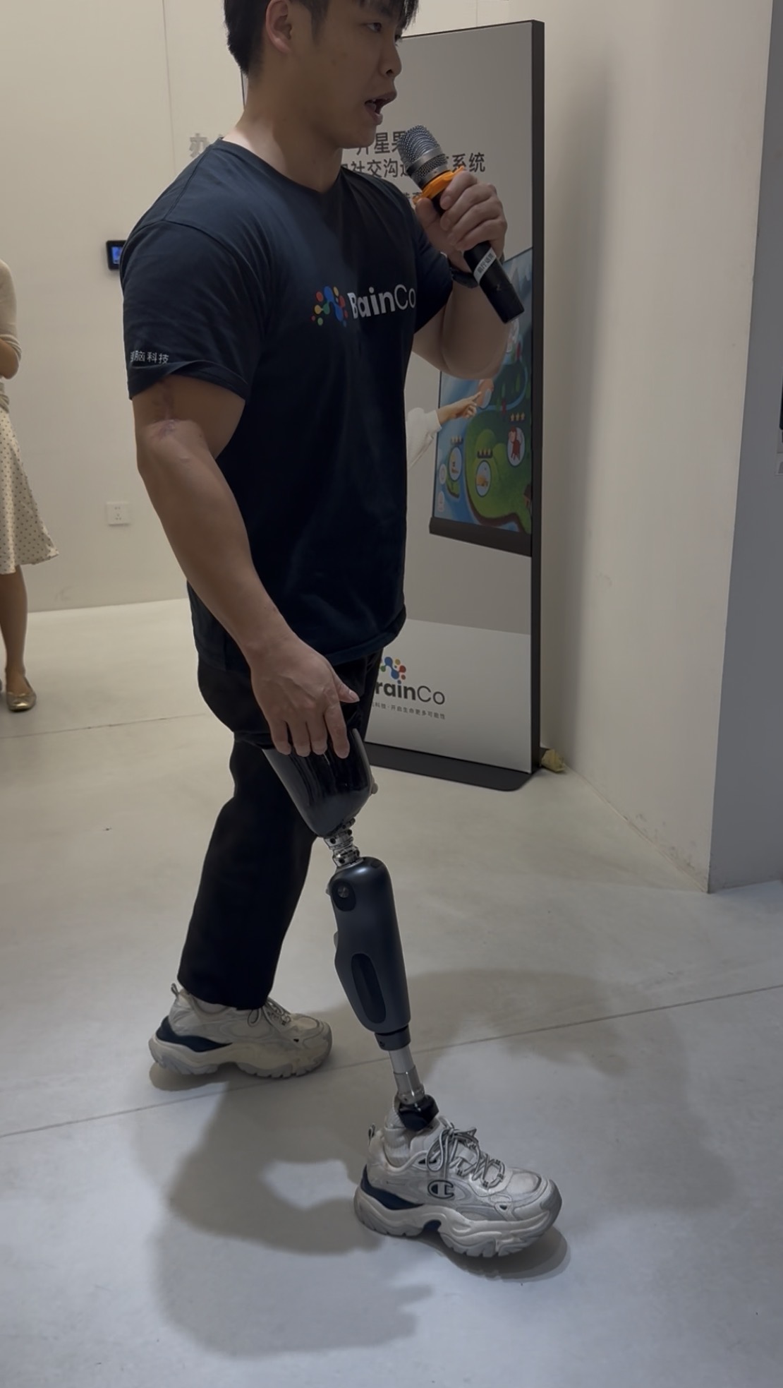 Personne présentant une prothèse de jambe bionique devant un panneau BrainCo