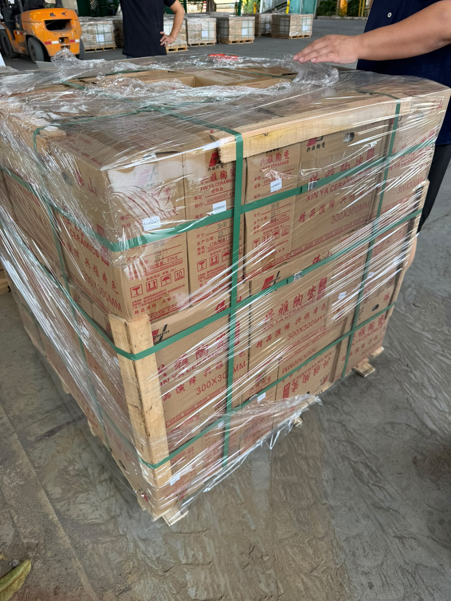 Palettes de cartons de carrelage 300x300 mm dans un dépôt en Chine, chariot élévateur en arrière-plan