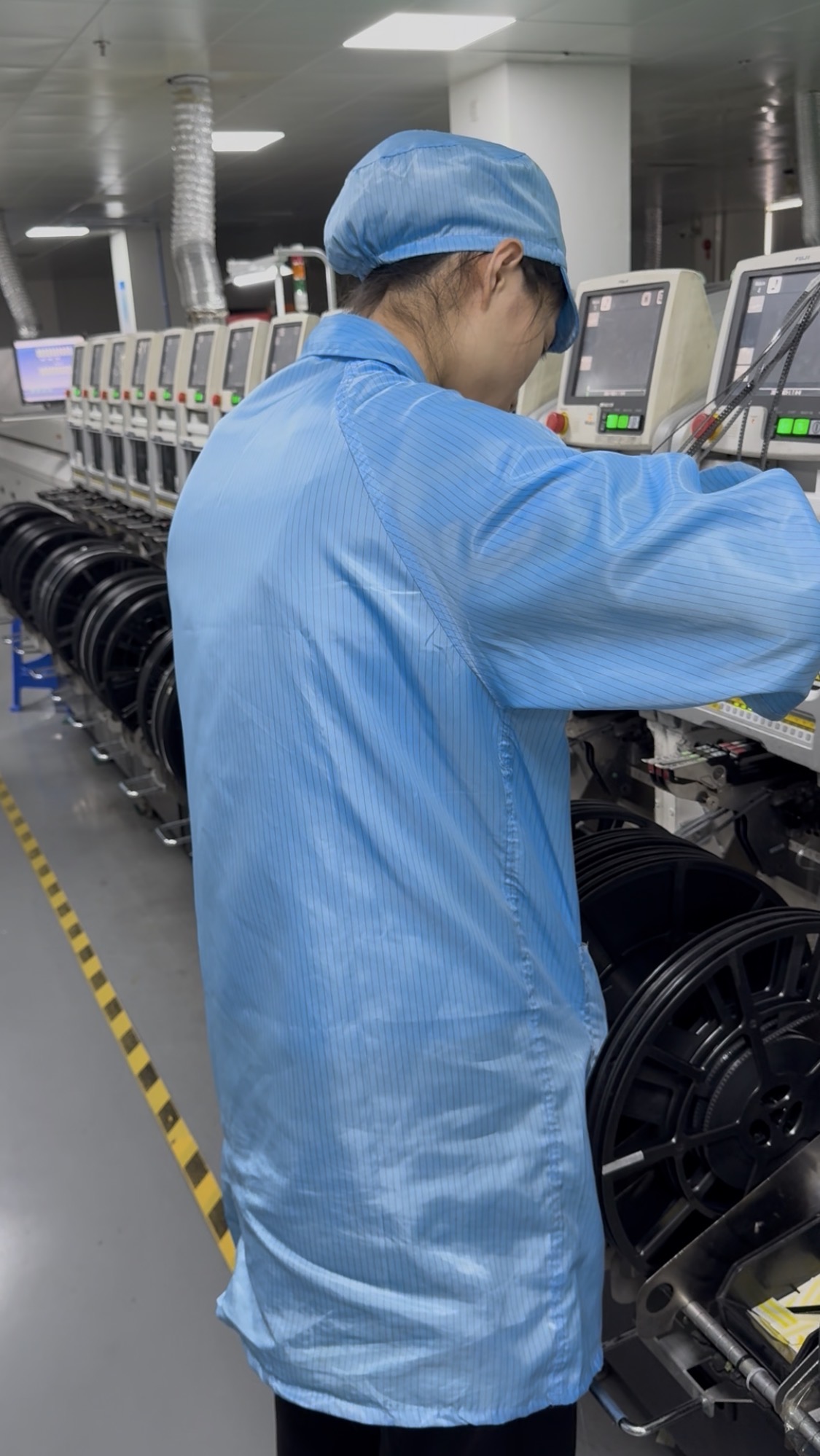 Opératrice chargeant les bobines de composants sur une ligne SMT